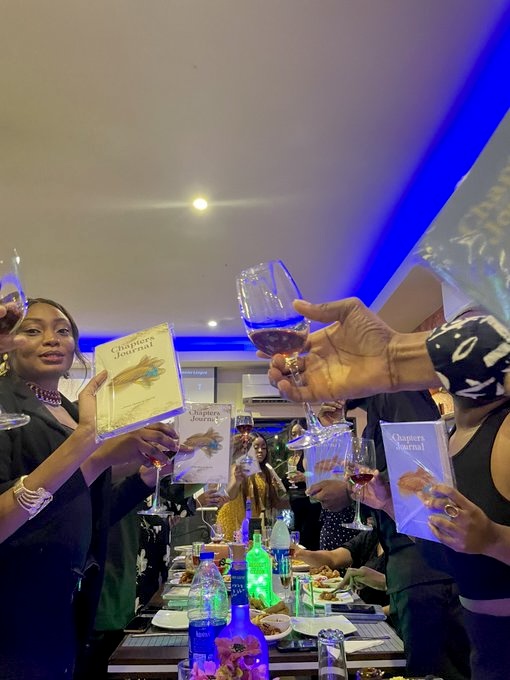A celebratory CHAPTERS Project gathering with participants holding CHAPTERS journals and raising glasses.